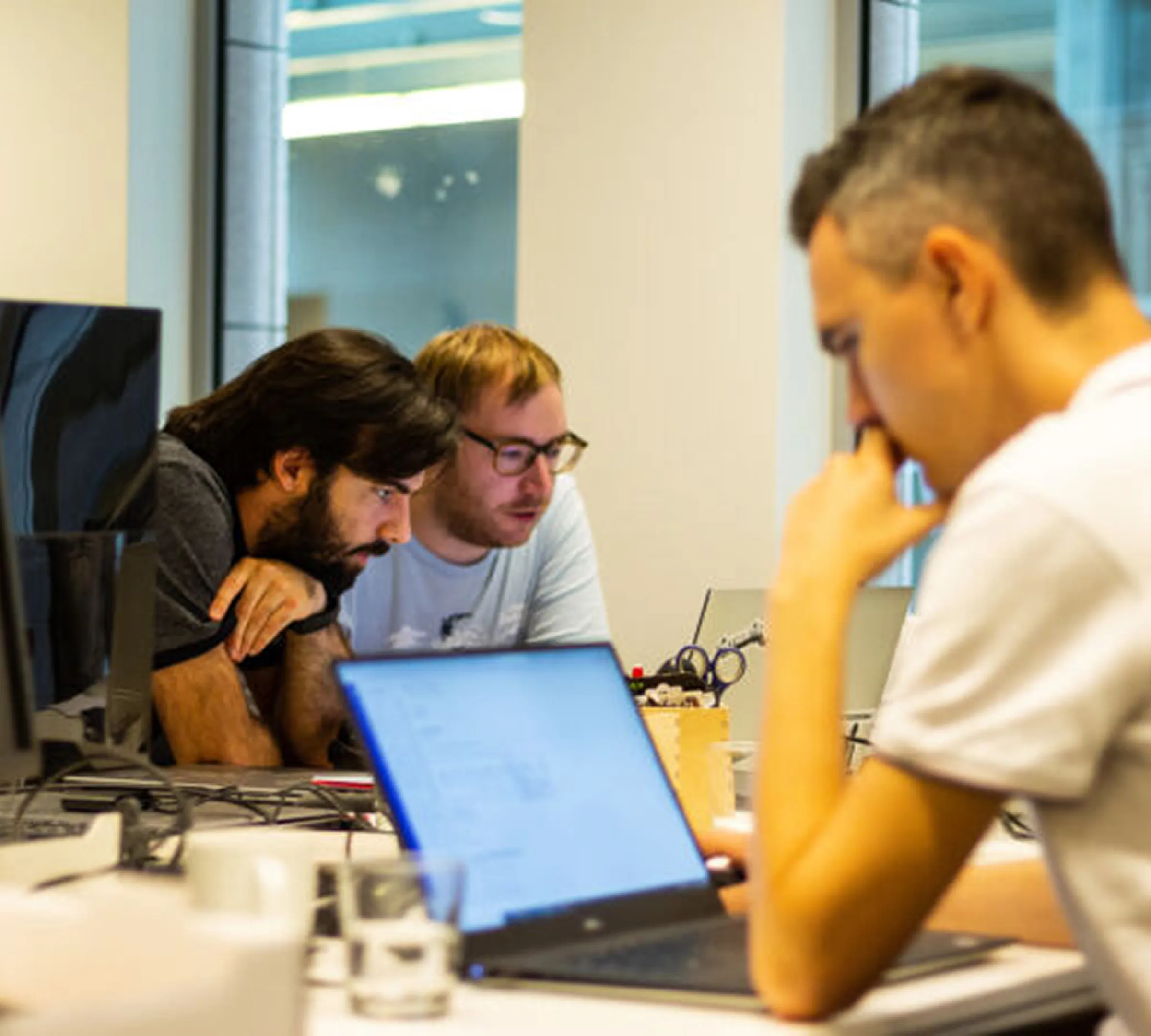 Drie collega's buigen zich samen over een laptop